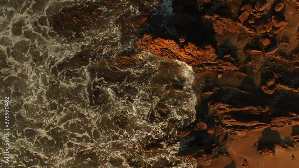 Ocean Water Crashing on Rocks and Shore with Red Blue and Orange Colors Ocean Water Crashing on Rocks and Shore with Red Blue and Orange Colors