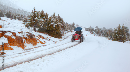 Old red tractor on a snow-covered winter road
