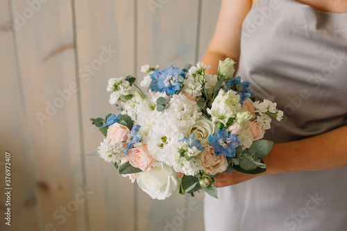 Very nice young woman holding big and beautiful colourful flower wedding bouquet