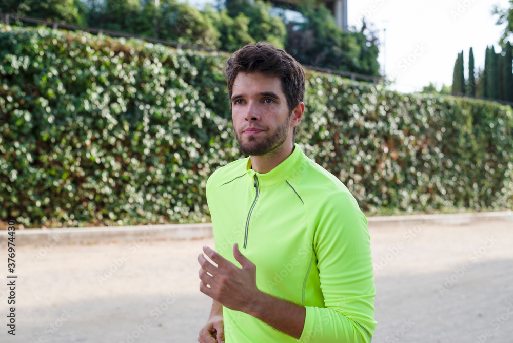 Attractive young man with a beard and yellow sportswear runs through the park. Lifestyle. Attractive young man with a beard and yellow sportswear runs through the park. Lifestyle.