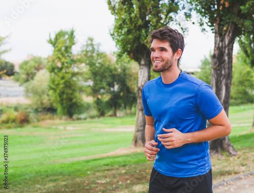 Young man dressed in sportswear with a beard laughs while running. Lifestyle.