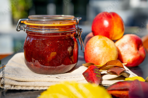 Nectarine jam and fresh nectarines. Homemade nectarine jam with fresh organic nectarines on wooden rustic background. Selective focus.  photo