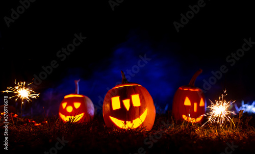 Halloween pumpkins over blue background with smoke with copy space.