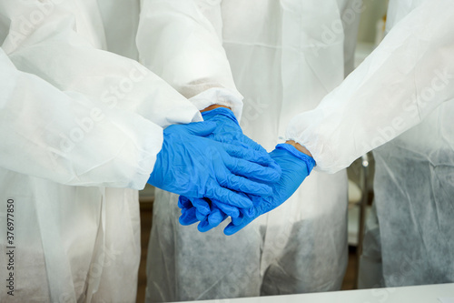 hands with protective lab blue gloves of four Asian medical scientists putting together. Teamwork of doctor diagnosis vaccine for corona covid-19 virus in science clinical laboratory
