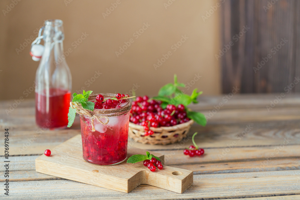 Glass of red currant cocktail or mocktail, refreshing summer drink with crushed ice and sparkling water on a wooden background. Glass of red currant cocktail or mocktail, refreshing summer drink with crushed ice and sparkling water on a wooden background.