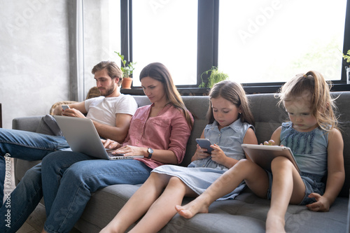 Modern family values. Father, mother and daughters using electronic devices.