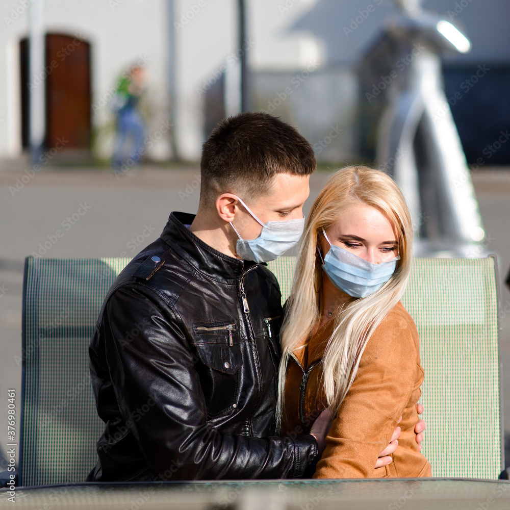 Young couple in love in protective medical mask on face outdoor at street. Young couple in love in protective medical mask on face outdoor at street.