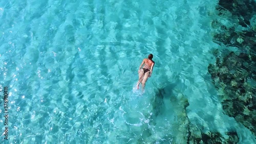 Young woman swimming in clean transparent blue sea. enjoying in refreshment of clear sea water
