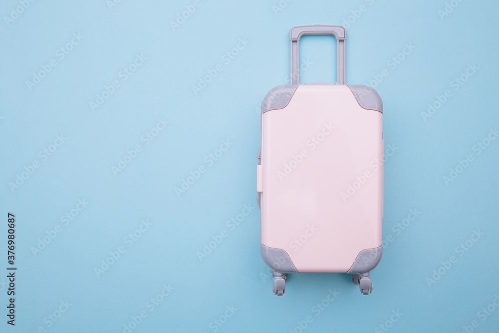 Mini travel luggage suitcase on blue background. Travel, beach, vacation concept. Mini travel luggage suitcase on blue background. Travel, beach, vacation concept.
