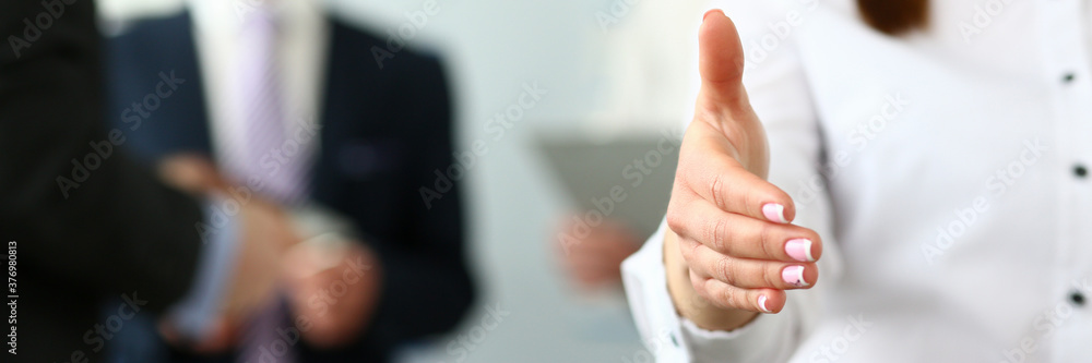 Obraz premium Focus on pretty female reaching tender arm to shake hands with biz colleague or boss manager to greet person. Company meeting concept. Blurred background