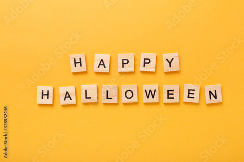 Text Happy Halloween on yellow background. Halloween concept. Flat lay, top view, copy space