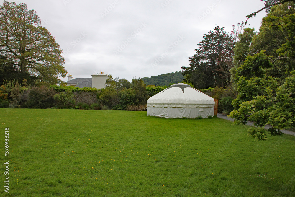 A traditional Mongolian yurt in the corner of a grassy field in England
