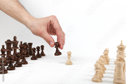 hand holding chess piece pawn on white background with other chess figures