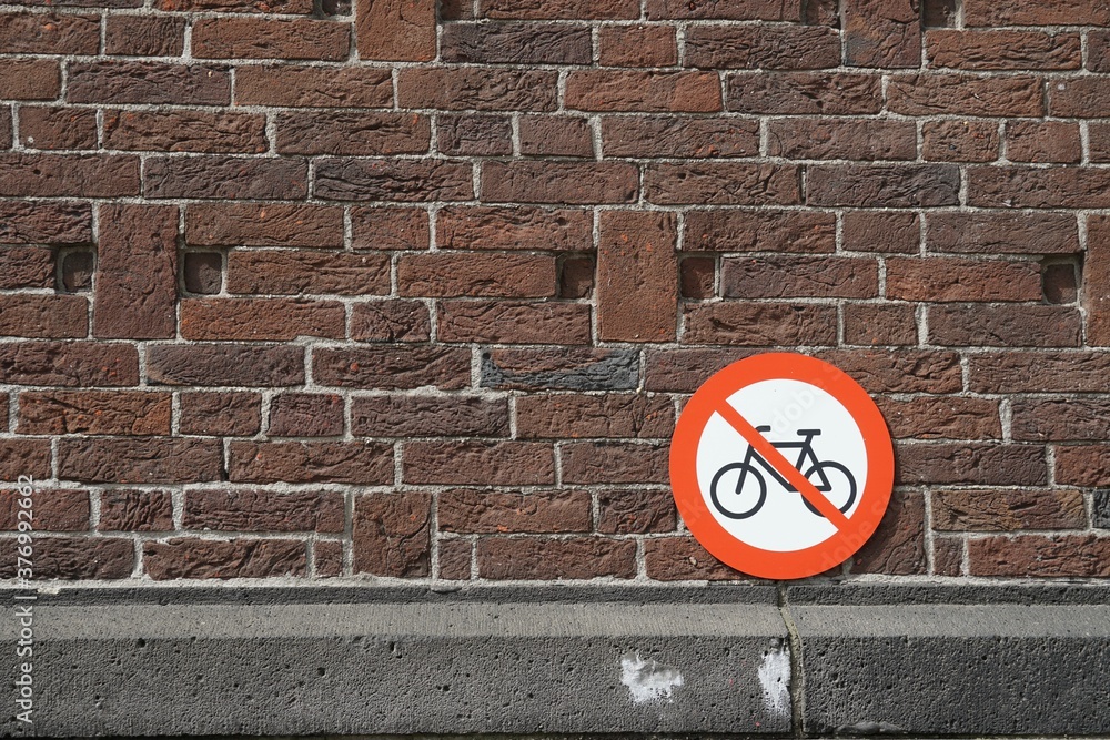 Bicycle parking prohibited, a round, metal sign leaned on a brick wall in the old city of Rotterdam, Netherlands, Europe. Bicycle parking prohibited, a round, metal sign leaned on a brick wall in the old city of Rotterdam, Netherlands, Europe.