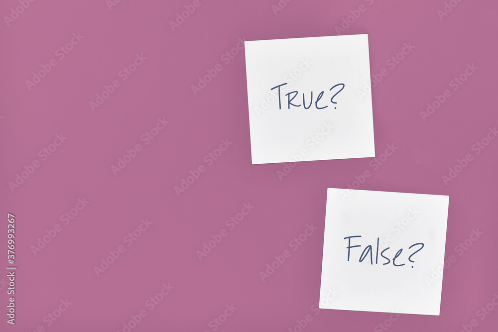 White sticky notes with words 'True?' and 'False?' on purple background White sticky notes with words 'True?' and 'False?' on purple background