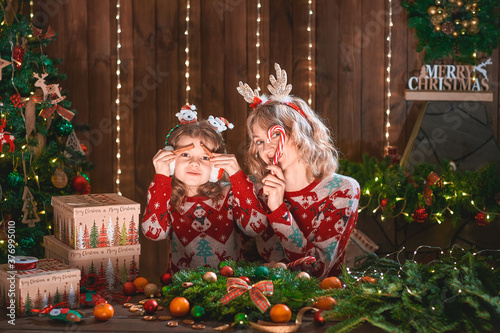 mother with child girl near christmas tree. new year holidays. happy family. woman with daughter having fun and smiling, making faces.
