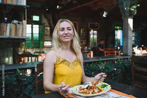 Content lady in summer top having meal in exotic restaurant
