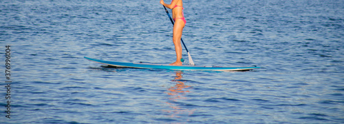 Young beautiful woman in a bikini on a SUP board in the river