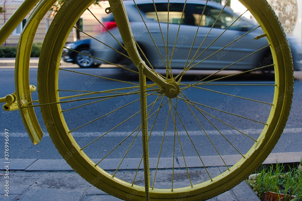 yellow bicycle wheel on blurred background of city traffic