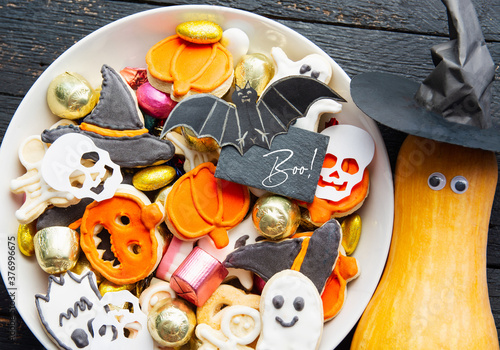 Halloween Jack o Lantern candy bowl with candy and halloween cookies, fresh pumpkin with eyes and witch hat. Trick or Treat on wooden background