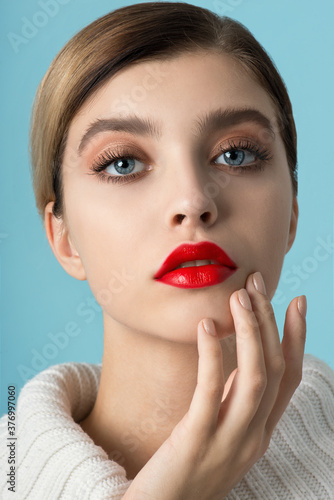 Portrait of beautiful young woman wearing red clothes with perfect young skin, red matt lips and nails.