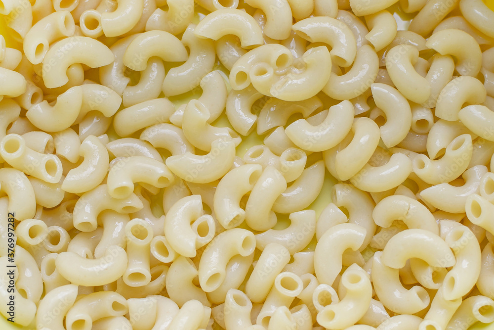 boiled pasta horns close up, yellow background boiled pasta horns close up, yellow background