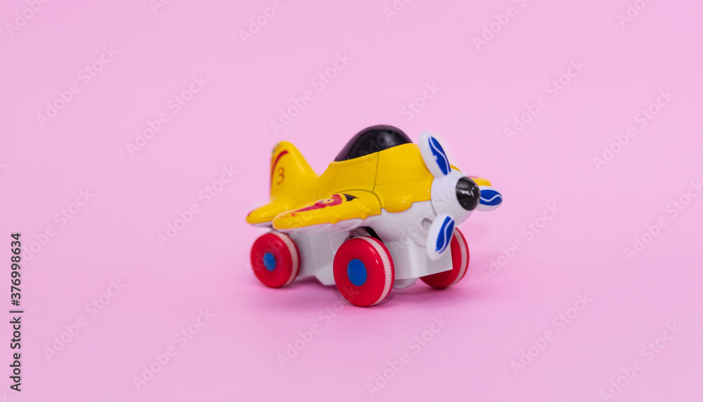 Toy plane in yellow on pink background Toy plane in yellow on pink background