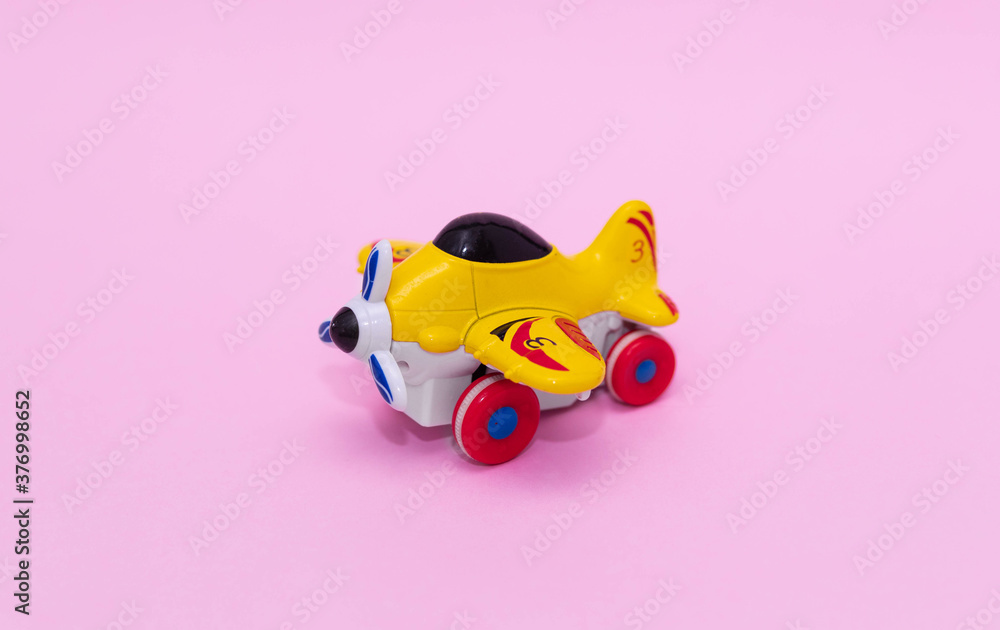 Toy plane in yellow on pink background