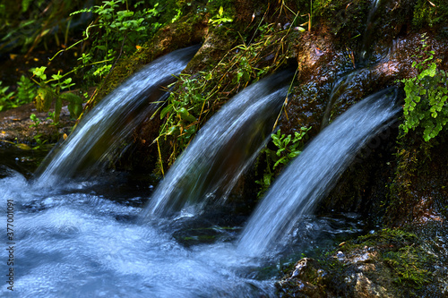Natural fountain in the forest, with three water pipes coming out of the rock