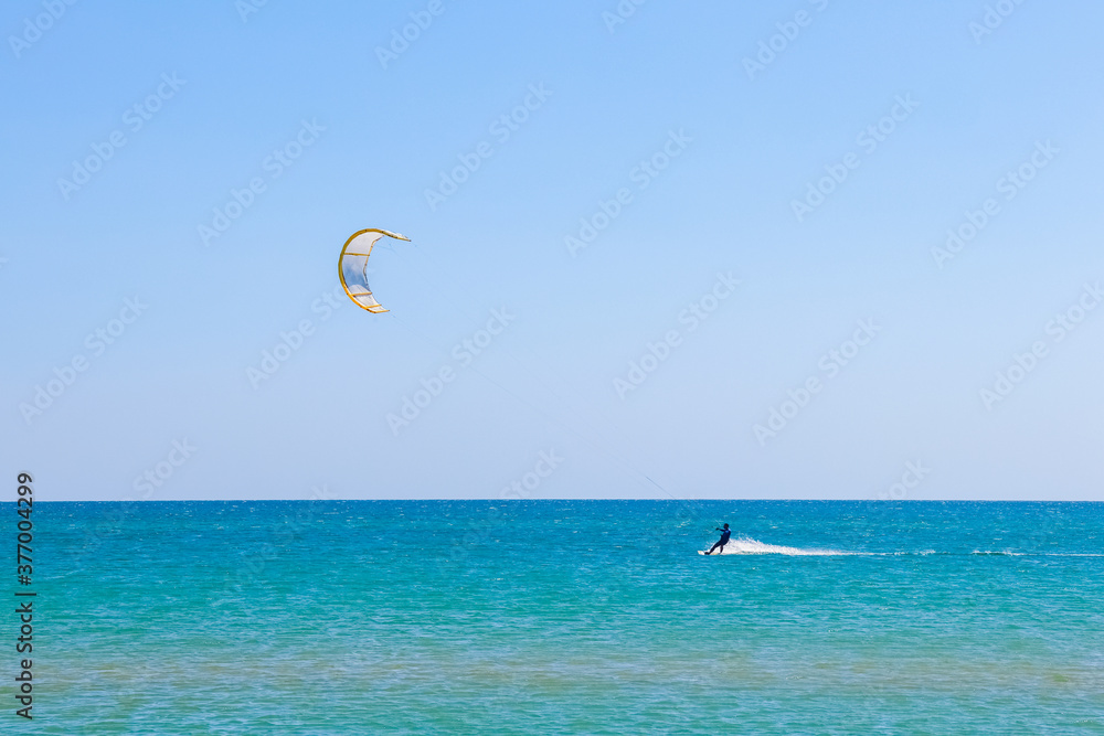 a kitesurfer surfing on the smooth azure water. recreational sport. A Man Rides A Kiteboarding In The Sea Water. extreme sport. Jump a kitesurfer surfing on the smooth azure water. recreational sport. A Man Rides A Kiteboarding In The Sea Water. extreme sport. Jump