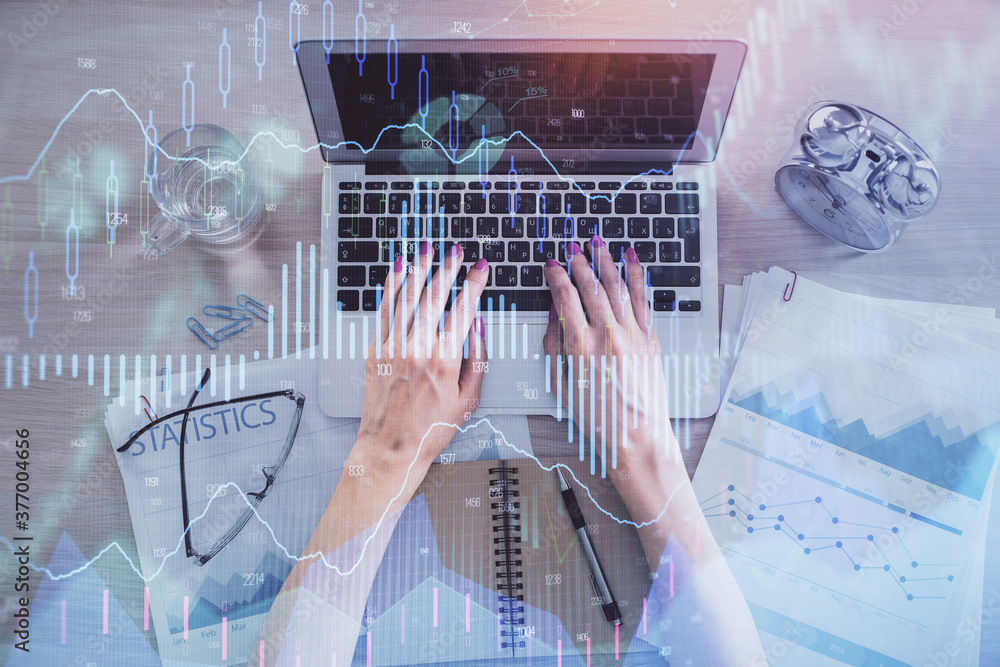Double exposure of woman hands working on computer and forex graph hologram drawing. Top View. Financial analysis concept. Double exposure of woman hands working on computer and forex graph hologram drawing. Top View. Financial analysis concept.