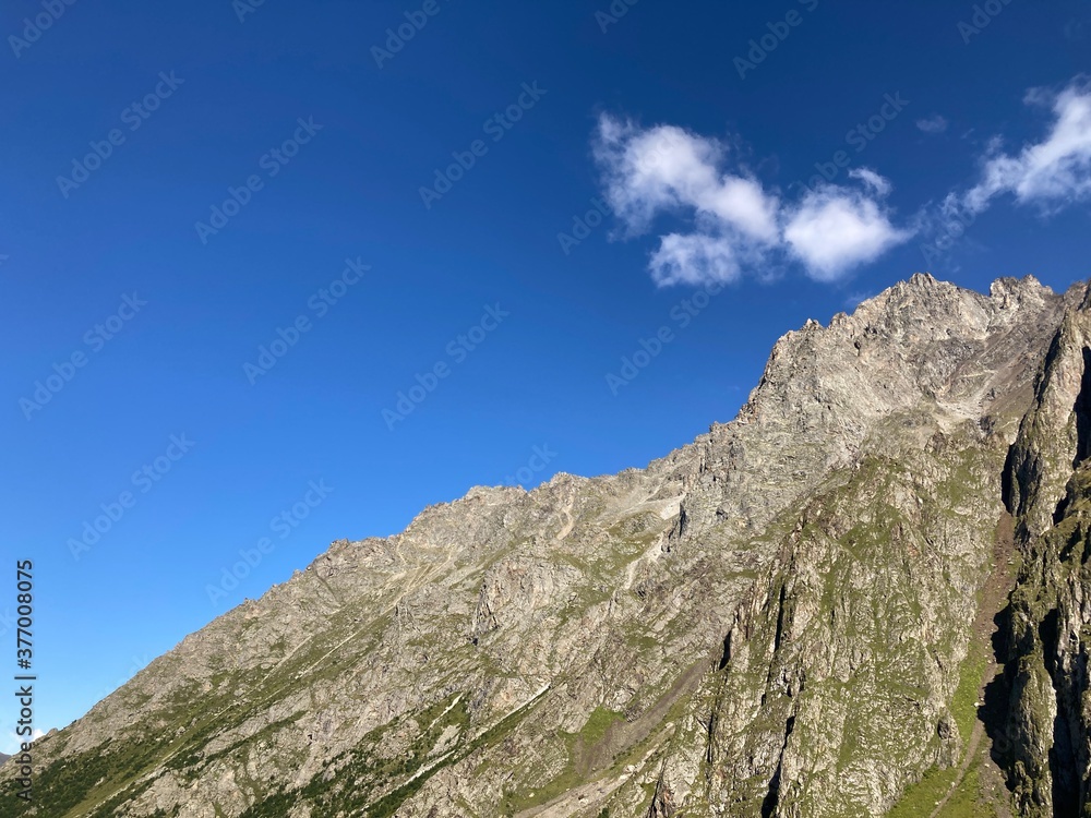 Mountain peaks against cloudy sky. Peaks of magnificent rocks located against bright cloudy sky on sunny day in nature.