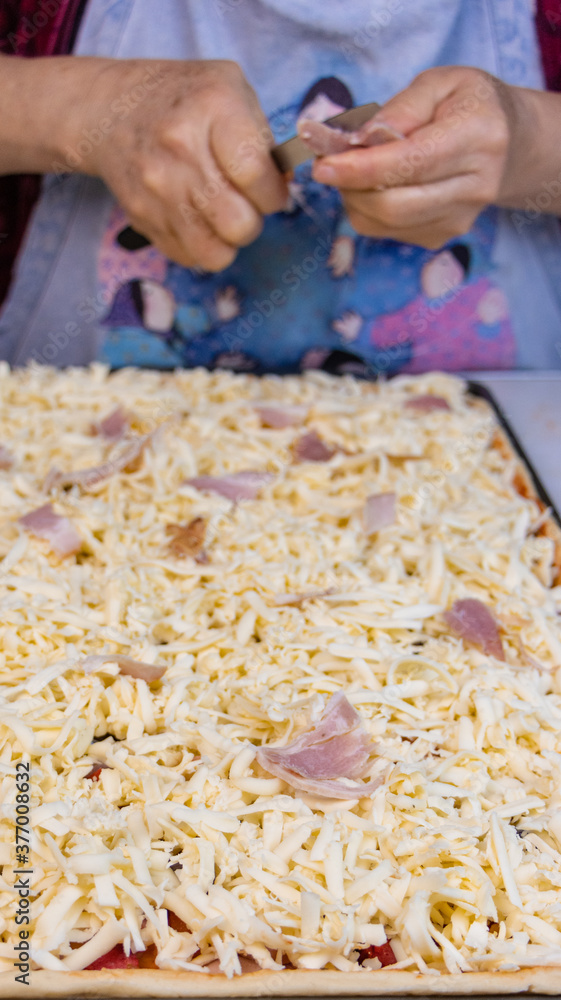 elderly woman white mother cutting sausages and sausages to make pizza