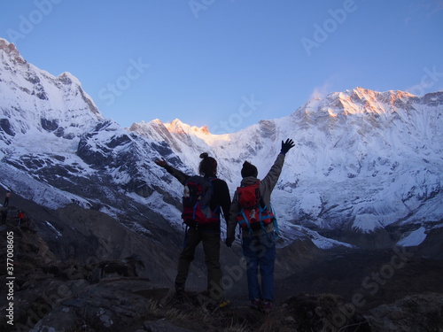 Mountain climbers raise their arms in front of a snow-covered Himalayas in the morning sun, ABC (Annapurna Base Camp) Trek, Annapurna, Nepal photo