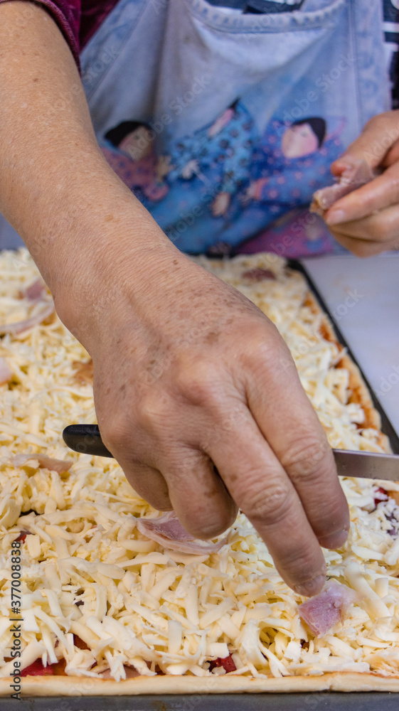 elderly woman white mother cutting sausages and sausages to make pizza