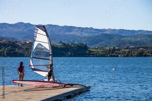 Two people on a dock trainin windsurf