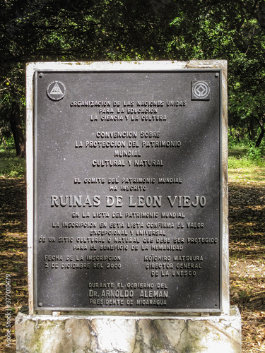 Leon, Nicaragua - November 27, 2008: Closeup of Black metal official plate at entrance to Ruinas de Leon Viejo museum park. Green foliage in back.