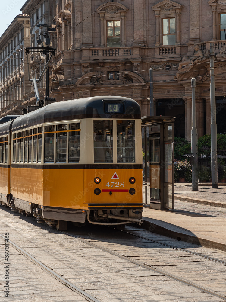 Fototapeta premium A yellow tram passes through the streets of the city of Milan