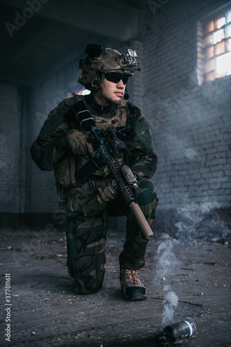 Military man during combat and smoke grenade on a ground.
