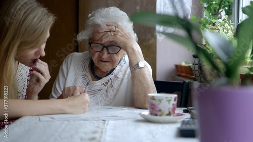 Young woman helping elderly grandmother with paperwork
