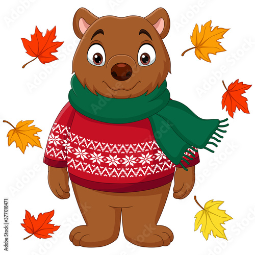 Cute brown bear in a sweater and scarf with autumn leaves