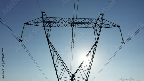 Transmission tower supporting an overhead high voltage power line - close up. The pylon carries wires that transport electric power from generating stations to electrical substations. Aerial footage.