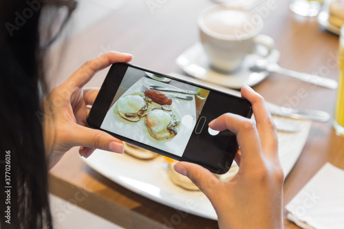 person holding with his hands cell phone to take a picture at breakfast, photo in the day