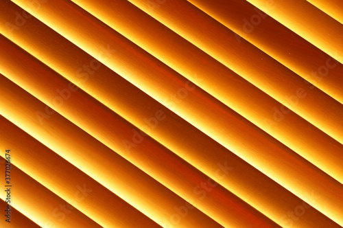 Abstract background - wooden blinds at an angle, large brown-gold horizontal stripes illuminated by the sun