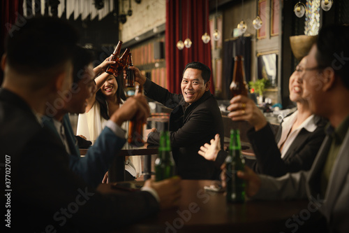 businesspeople toasting and clinking bottle of beer together