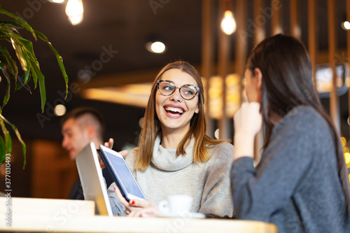 Two girls having a meeting at a modern cafe. Happy smiling expressions, © Nikola Spasenoski