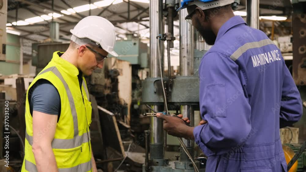 Two factory worker talking about maintenance and check the industrial machine working in manufacturing plant. Two factory worker talking about maintenance and check the industrial machine working in manufacturing plant.