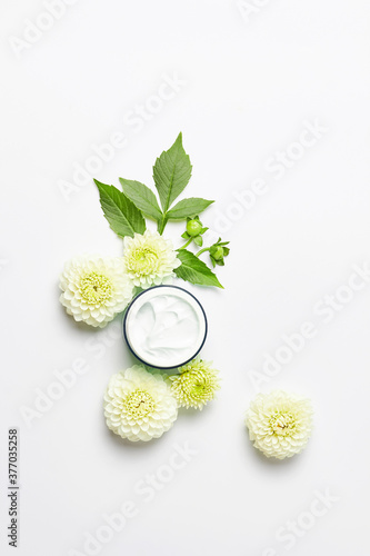skincare and body care concept. fresh white flowers on a light background. bottle of moisturizer cream. simple flat layout, vertical frame