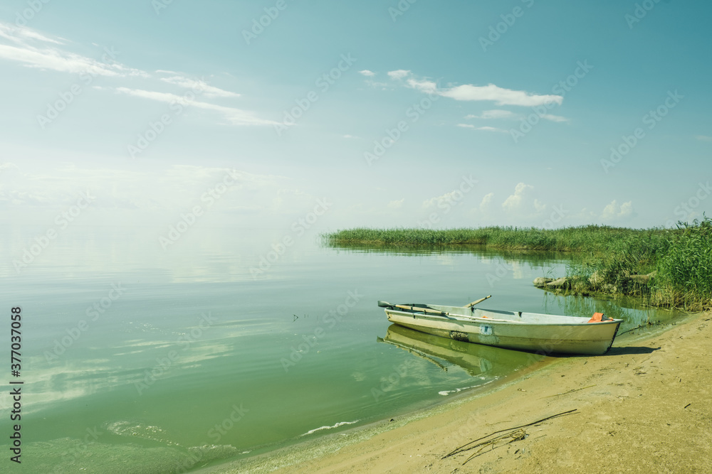 The beautiful landscape of a white simple wooden boat on the big blue lake. Concept vacation on the lake. Good summer day in nature.