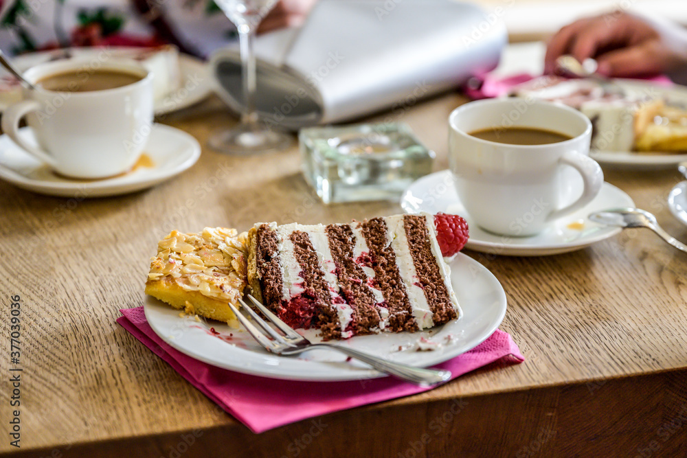 fork on top of a piece of multi layer wedding cake with a cup of coffe on table fork on top of a piece of multi layer wedding cake with a cup of coffe on table